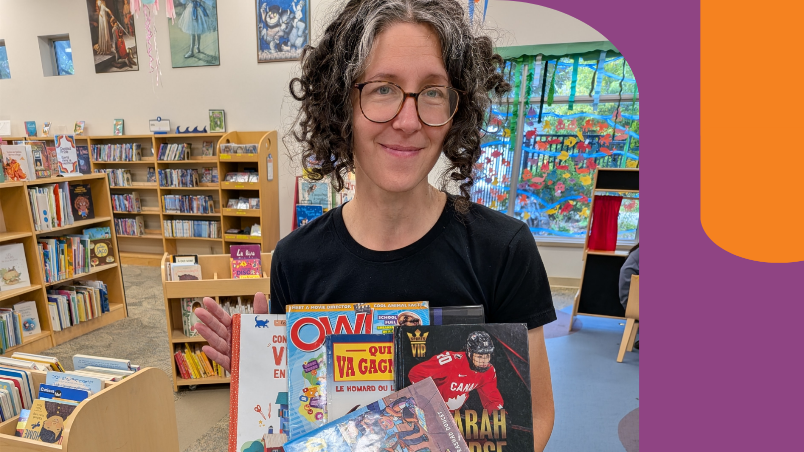 Josée standing in front of the children section and holding children books.